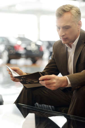 Now I see the advantages  Confident senior businessman reading a car magazineの写真素材