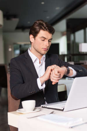 Handsome businessman looking at the watch. Checking his timeの写真素材