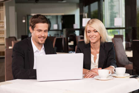 Business couple working with laptop at coffee. While having business lunch.の写真素材
