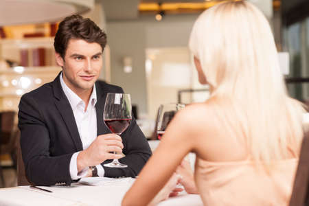 Attractive man with wine glass looking at beautiful woman. Trying to seduceの写真素材