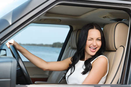 An attractive young Caucasian woman winking at the camera from the front seat of the carの写真素材