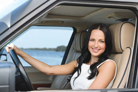 An attractive young Caucasian woman looking at the camera from the front seat of the carの写真素材