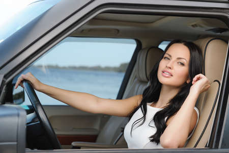 An attractive young Caucasian woman looking at the camera from the front seat of the carの写真素材