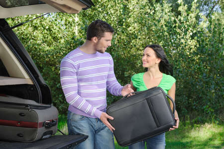 An attractive young couple packing the luggage into the trunkの写真素材