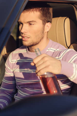 Young man drinking alcohol while driving a carの写真素材