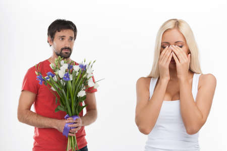 Please, donï¿½ cry! Young handsome men holding a bunch of flowers while his girlfriend crying on...