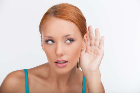 I will keep your secret. Beautiful young woman listening to the gossip while isolated on whiteの写真素材