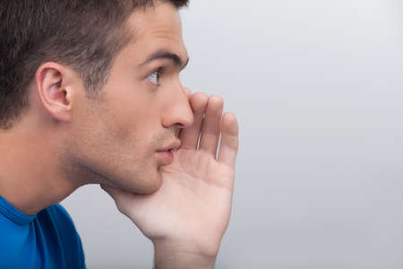 Men telling gossips. Handsome young men gossiping while standing isolated on whiteの写真素材