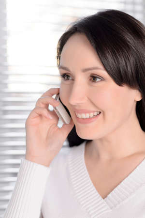 Portrait of beautiful middle-aged woman talking at phoneの写真素材