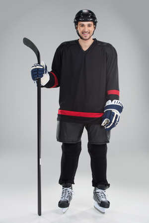 Attractive hockey player in uniform. Standing full length isolate on greyの写真素材