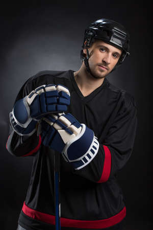 Attractive young hockey player posing on camera. Standing isolated on blackの写真素材