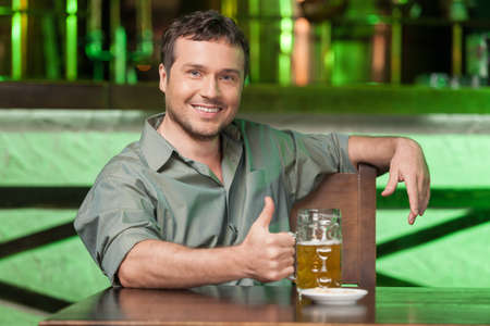 Night in bar. Portrait of cheerful men drinking beer at the barの写真素材
