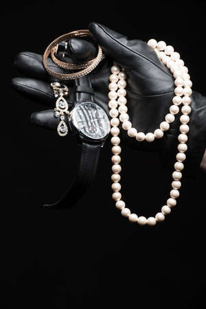 Stolen goods. Close-up of hand in gloves holding stolen goods against black backgroundの写真素材