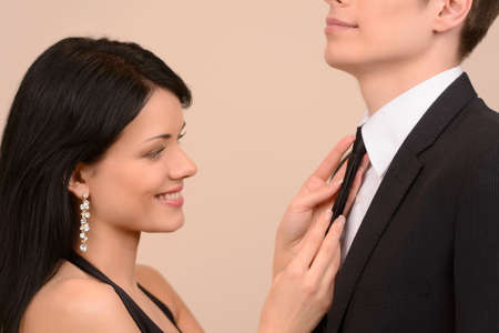 Tying his tie. Beautiful young woman tying his boyfriends tieの写真素材