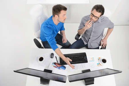 Discussing business plan. Top view of two businessmen dicussing something while one of them pointing computer monitorの写真素材