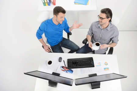 Discussing the project done. Top view of two businessmen dicussing something while drinking coffee at theri working placesの写真素材