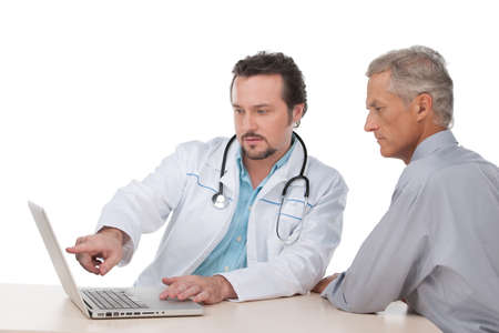 Doctor in white robe showing on laptop test results to his patient. Sitting over white backgroundの写真素材