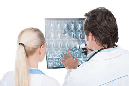 Male doctor showing his female assistant roentgen of patient. Back view isolated on white.の写真素材