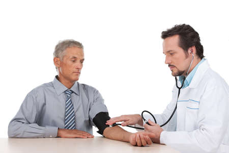 Adult doctor checking pressure of old patient. Looking serious, sitting isolated on whiteの写真素材