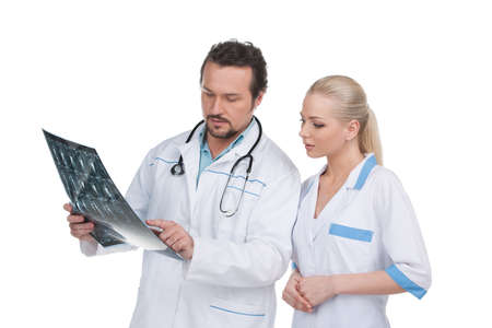Couple of doctors discussing X-ray of the patient. Standing isolated on whiteの写真素材
