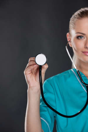 Close up of young female doctor with stethoscope on foreground. Cut out of face isolated on black backgroundの写真素材