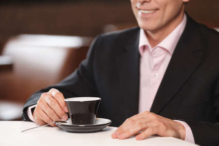 Men with cup of coffee. Cropped image of businessman drinking coffee at restaurantの写真素材