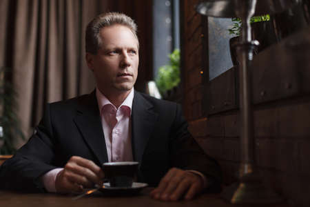 Man drinking coffee at the restaurant Thoughtful mature businessman drinking coffee at the restaurantの写真素材
