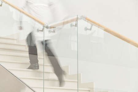 Hurry to save a life. Blur motion of doctor in white uniform hurrying and running upstairsの写真素材