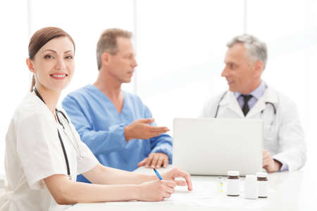 Young and ambitious. Portrait of a smart young female doctor sitting at the table in front of her colleagues and smilingの写真素材