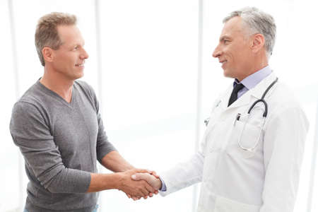 Thankful patient. Thankful mature patient shaking doctors handの写真素材