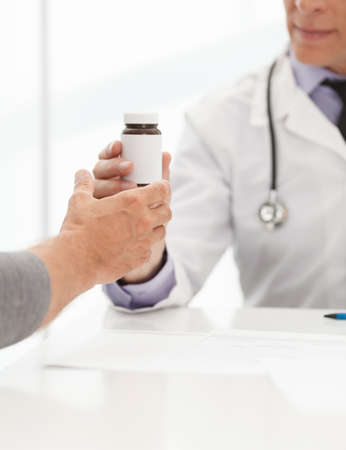 Prescribed medicines. Doctor giving a bottle of pills to the patientの写真素材