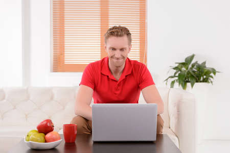 Men surfing web. Handsome young men sitting on the couch and using computerの写真素材