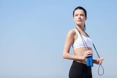 Women with jumping rope. Beautiful young women standing with a jumping rope in her hands with a sky...
