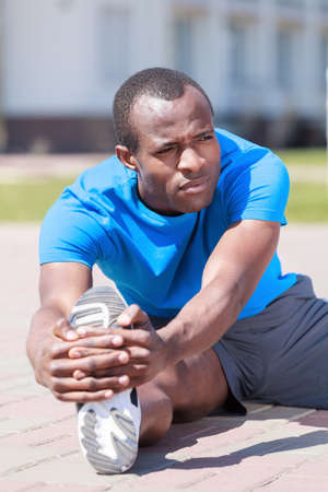 Exercising before jogging. Young african decsent men doing his outdoors exercisesの写真素材
