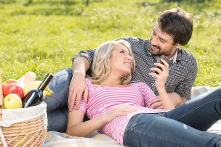 Listening to the music together. Loving young couple listening to the music on picnic togetherの写真素材
