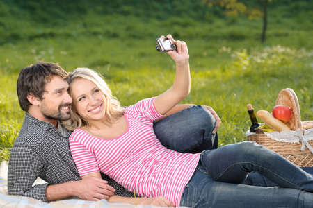 It will be the great shot. Loving young couple taking the photographs of themselves on summer picnicの写真素材