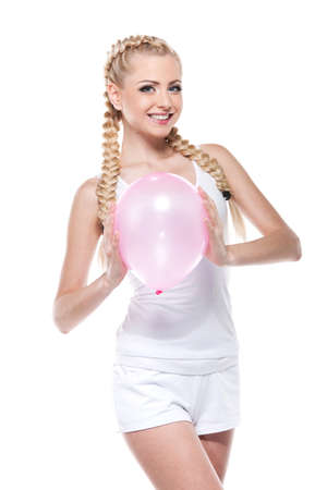 Sexy cute blond girl holding pink balloon and smiling. Standing and posing isolated over white backgroundの写真素材