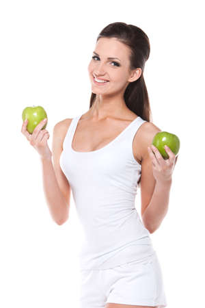 Healthy slim young woman with two green apples. Fashion posing isolated over white  backgroundの写真素材