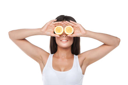 Funny brunet girl holding two halves of lemon instead of eyes. Idea of keeping healthy life styleの写真素材