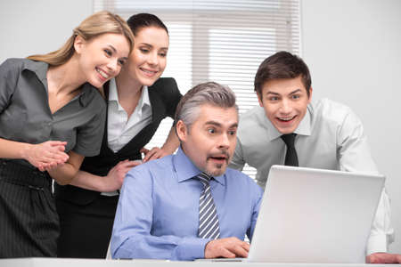 Surprised business team looking on laptop with laughing. Having fun at working place.の写真素材