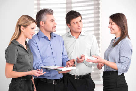 Beautiful middle aged female shearing her opinion with business team. Stylish successful business people in modern officeの写真素材