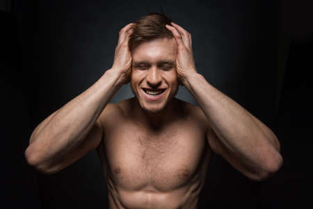 Portrait of sexy shirtless fit man holding his head. Concept of complete lost or panicの写真素材