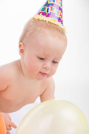 Funny cute little baby playing with yellow balloon. Looking away isolated over white backgroundの写真素材