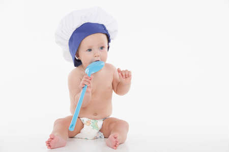Cute little baby in toque with ladle. Sitting isolated over white backgroundの写真素材