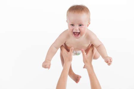 Close up of mother hands throwing up little baby. Cute baby laughing isolated over white backgroundの写真素材