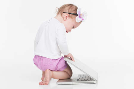 Cute little baby girl playing with laptop. Full length shoot isolated on white backgroundの写真素材