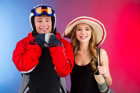 Close up of couple in different seasonal clothes. Idea of woman having summer vocation and man having winter vocationの写真素材