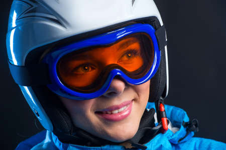 Portrait of happy smiling sportswoman with beautiful eyes in helmets. Standing isolated over black...