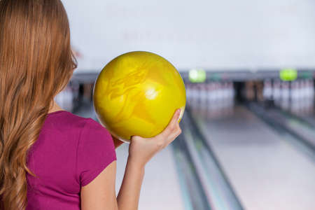 Bowling. Closeup of woman holding a bowling ball focusing for a roll,rear view.の写真素材