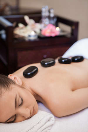 girl laying on massage table. dark stone laying on backの写真素材